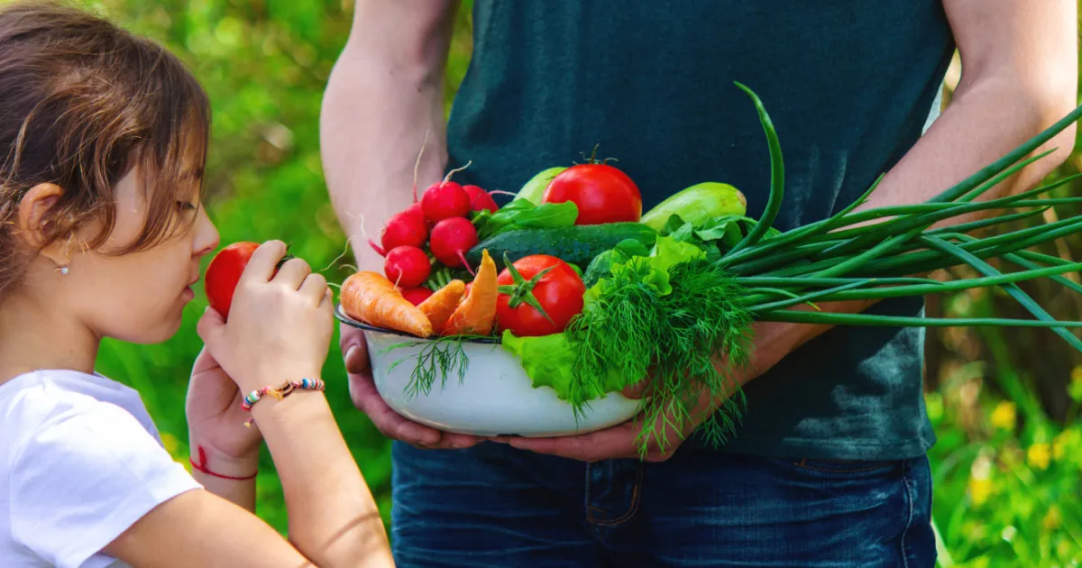 Un papa et sa fille avec les légumes du jardin