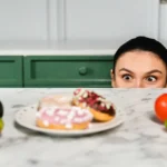 Dépendance au sucre : jeune femme tiraillée entre des aliments sains et ultra-transformés